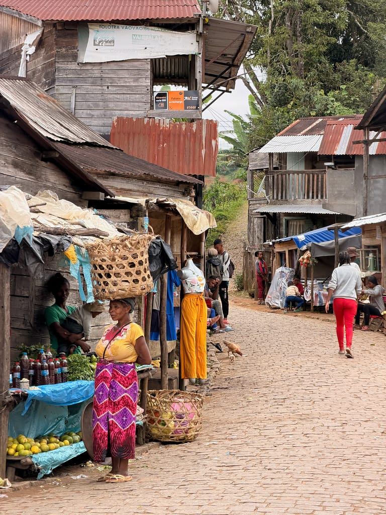 Préparer un voyage à Madagascar : guide complet, visa, budget, vaccins Andasibe Madagascar rues et femme au panier sur la tête