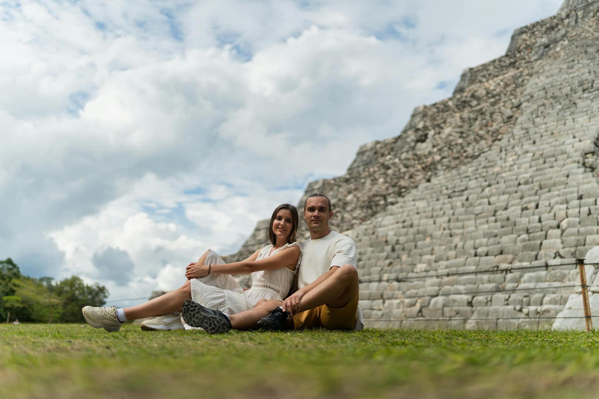 Budget 2 semaines de voyage en Chine Happy couple sitting near ancient Mayan pyramid in Yucatan, enjoying a sunny day outdoors.