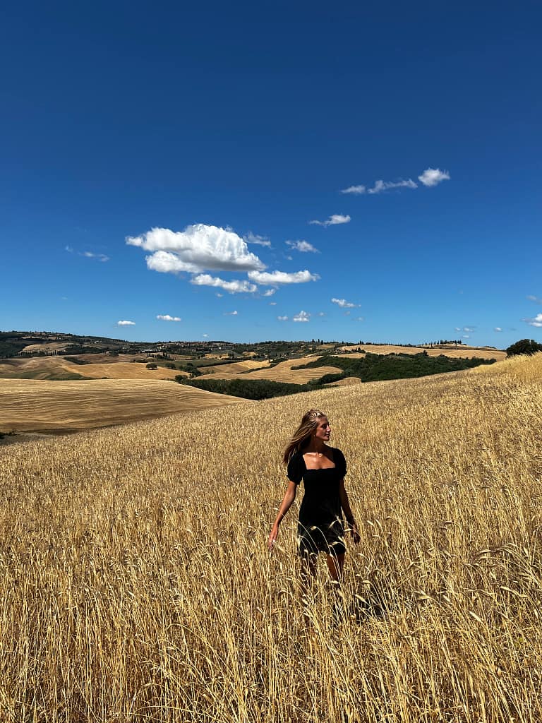 toscane italie paysage champs doré avec voyageuse aux cheveux dans le vent